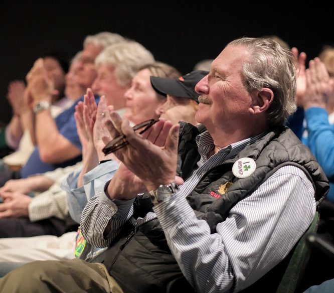 Audience members smiling and clapping
